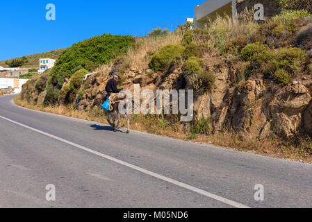 NAXOS, Griechenland - 24. Mai 2017: Alter Mann, der auf einem Esel auf der Straße auf der Insel Naxos. Stockfoto