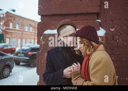 Junger Mann und eine Frau, die in der Nähe von Backstein Ecke des Gebäudes. Winter Straße. Datenschutz in der abgelegenen Orten in der großen Stadt Stockfoto