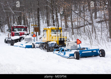 Zwei Schneemobil-trail Piste, Bombardier eine Gelbe und eine Rote Pisten Bully, auf der Perkins Clearing Straße in den Adirondacks geparkt. Stockfoto