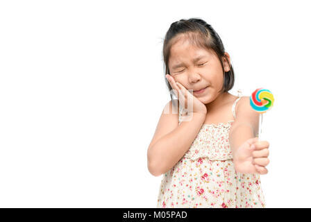 Wenig asiatisches Mädchen leiden unter Zahnschmerzen und Holding candy in der Hand auf weißem Hintergrund, zahnmedizinisches Problem Konzept Stockfoto