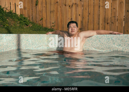 Schönen fetten Mann, der Reisen im Sommer Urlaub und Sitzen im Land Villa Pool entspannen Träumen. Stockfoto