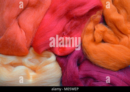 Rovings Merino Wolle in verschiedenen Farben orange, pink und lila gefärbt und arrangiert eine abstrakte Formen zu bilden. Stockfoto