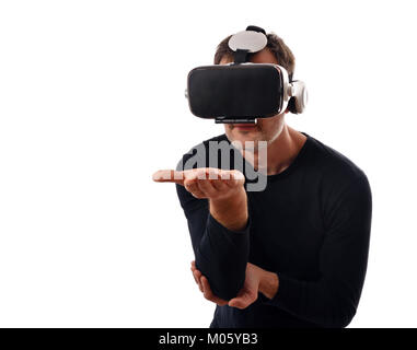 Lächelnder Mann mit schwarzen Pullover und Virtual reality Brillen Interaktion mit Hand vor ausgestreckt. Horizontale Komposition. Weiß isoliert Stockfoto