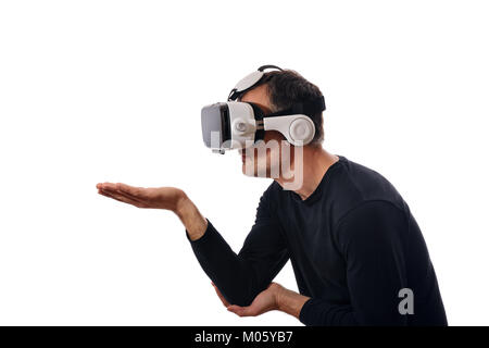 Lächelnder Mann mit schwarzen Pullover und Virtual reality Brillen Interaktion mit Hand in die seitliche Position ausgestreckt. Horizontale Komposition. Isolieren Stockfoto