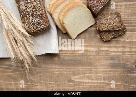 Schnitt mit Schichten und Vollkornbrot auf einem Holzbrett. Ein Laib frisches rustikale Mahlzeit Roggenbrot, auf einem Holzbrett, ländliche essen Hintergrund geschnitten. Stockfoto