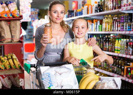 Positive Mutter mit Jugendmädchen Demonstration ihrer Wahl in Essen Abteilung im Supermarkt Stockfoto