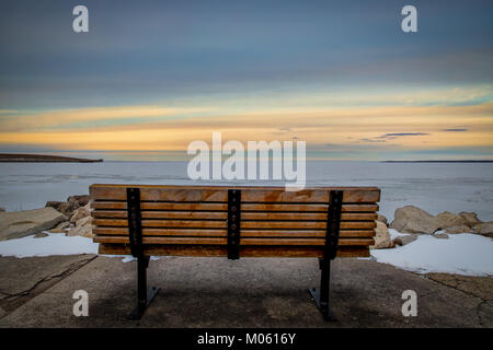 Eine Parkbank mit Blick auf den gefrorenen Gewässern von Green Bay, WI. Stockfoto