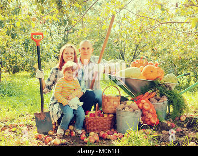 Glückliche Eltern und Kind mit geernteten Gemüse im Garten Stockfoto