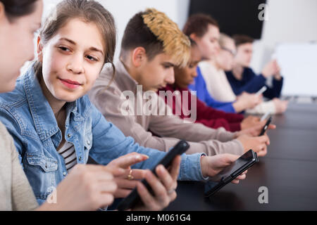 Happy Mitschüler über ihre Smartphones intensiv während der Klassen Stockfoto