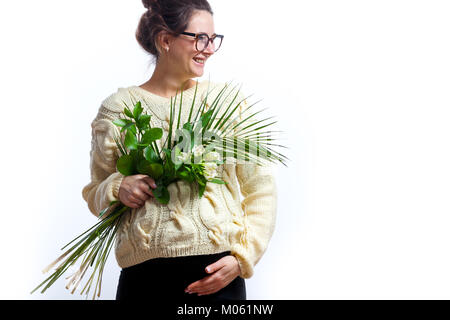 Eine junge Frau in einem gestrickten Milch - farbige Pullover in Schwarz gekleidet und trägt eine Brille auf Ihrem letzten Schwangerschaft hält einen Blumenstrauß und smilin Stockfoto