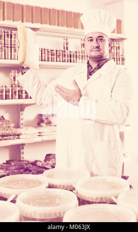 Happy europäischen shop Personal bietet Lebensmittel und gefüllten Regalen hinter Stockfoto