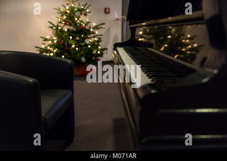 Grand Piano mit Weihnachtsbaum im Hintergrund Stockfoto