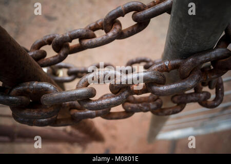 Alte verrostete Ketten halten das Tor geschlossen. Von oben in enger mit geringer Tiefenschärfe Ansicht angezeigt. Halten Sie oder ist es halten Sie? Stockfoto