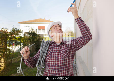 Mitte - Alter Builder mit Rollen von Kabel über seine Schulter outsied Stockfoto