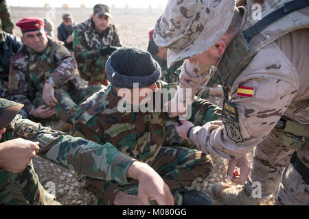 Ein spanischer Soldat nach La Legion Infanterie zugeordnet, gilt ein stauschlauch, der über eine irakische Soldaten des Bataillons 25 Anbar, Polizei, während eine taktische Unfallversicherung care Klasse am Lager Besmaya, Irak Jan. 7, 2018. Die Schulung ist Teil des gesamten Combined Joint Task Force - inhärenten Building Partner Kapazität mission lösen, die über die Ausbildung und die Verbesserung der Fähigkeit der zusammengeschlossen, um Kräfte, die ISIS konzentriert. CJTF-OIR ist die globale Koalition zu besiegen ISIS im Irak und in Syrien. (U.S. Armee Stockfoto