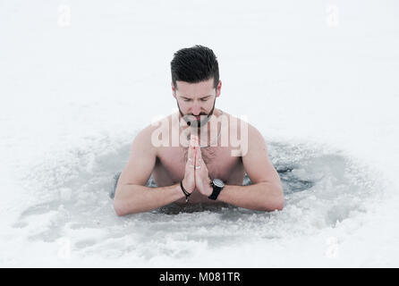 Junger bärtiger Mann Meditation in einem zugefrorenen See Stockfoto
