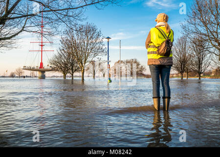 Frau in überfluteten Straße in wellys Stockfoto