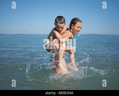 Kleines Mädchen und der kleine Junge spielt in Wasser Stockfoto