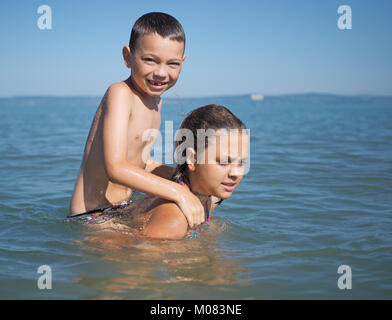 Kleines Mädchen und der kleine Junge spielt in Wasser Stockfoto