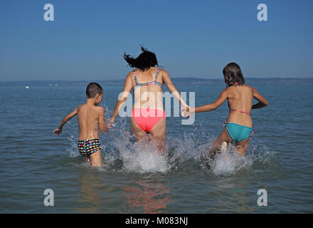 Mutter mit ihren Kindern beim Spielen im Wasser