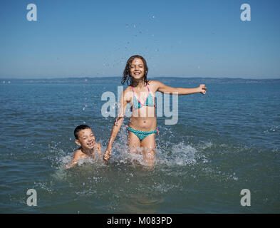 Kleines Mädchen und der kleine Junge spielt in Wasser Stockfoto