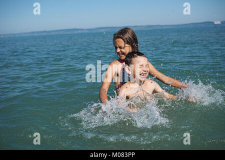 Kleines Mädchen und der kleine Junge spielt in Wasser Stockfoto