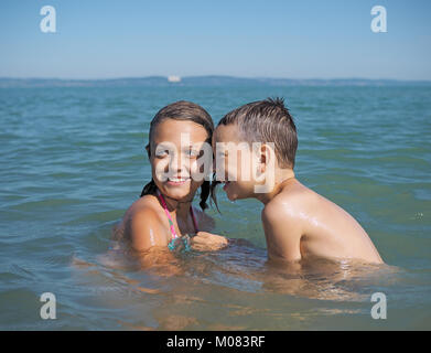 Kleines Mädchen und der kleine Junge spielt in Wasser Stockfoto