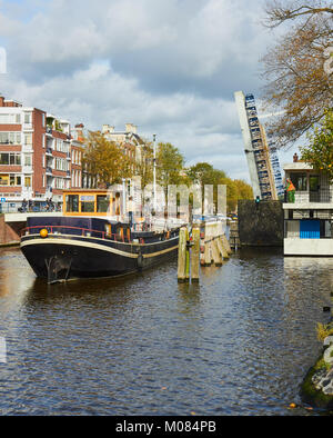 Barge, die durch eine Klappbrücke über Hortusbrug Nieuwe Herengracht Kanal, Amsterdam, Niederlande Stockfoto