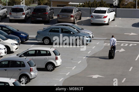 Kapstadt Südafrika. Dezember 2017. Mann ziehen Gepäck zu einem Auto auf einem Parkplatz auf dem Dach Stockfoto