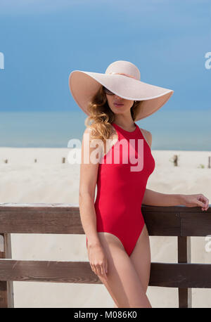 Schöne Frau in einem roten Badeanzug in einen Hut am Strand Schöne Frau in einem roten Badeanzug in einen Hut am Strand Stockfoto