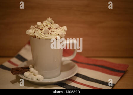 Essen und Trinken fotografie Bild einer frischen home Hot Chocolate Drink in eine weiße Tasse oder Becher mit Schlagsahne und Marshmallows auf rustikalen Holz Stockfoto