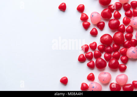 Die verstreuten Valentinstag zimt Herz Bonbons mit rot und pink Jelly Beans auf weißem Hintergrund Stockfoto