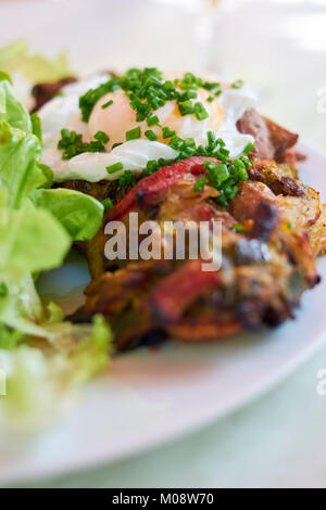 Ein tartine Forestiere a Wild Mushroom Tartine mit pochiertem Ei und gehackten Schnittlauch mit Salat gekleidet. Stockfoto