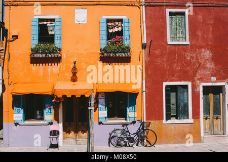 Orange House und ein Fahrrad an einem sonnigen Tag in Insel Burano, Venedig, Italien. Stockfoto