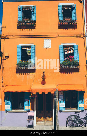 Orange House und ein Fahrrad an einem sonnigen Tag in Insel Burano, Venedig, Italien. Stockfoto