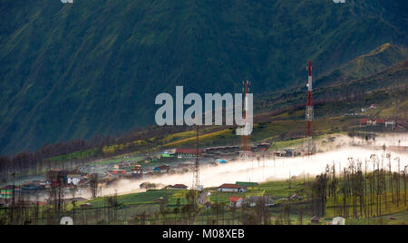 Misty fließt durch das Dorf am frühen Morgen, als die Sonne, Bromo, Indonesien Stockfoto