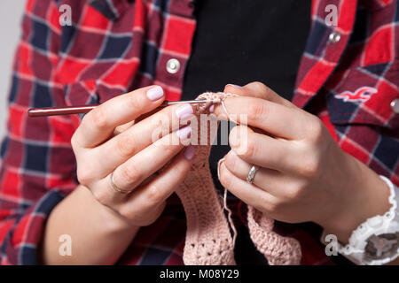 Nahaufnahme einer verheirateten Frau in einem karierten Hemd und mit einem weißen Uhr strickt ein rosa Oberteil Stockfoto