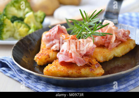 Geriebenen Bratkartoffeln mit Speck, im Hintergrund gekochten Brokkoli und Kartoffeln Stockfoto