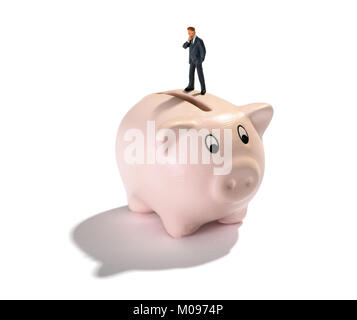 Studio shot Nahaufnahme einer Miniatur Figur Mann denken, der Ersparnisse und Gewinne, während auf einem sparschwein vor weißem Hintergrund steht für Copy space Stockfoto