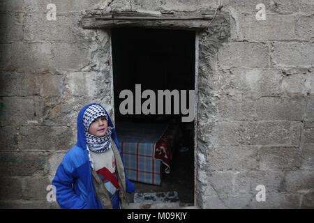 Mesraba, Syrien. 18 Jan, 2018. Ein Junge gesehen, ein Schal ihn warm im Winter zu halten, während neben einem alten Shop vorbei. Trotz des anhaltenden Konflikts in Syrien, Leben in der Regierung - statt Teile von Damaskus und rund um die Hauptstadt, trägt noch auf relativ friedlich. Damaskus, die Hauptstadt von Krieg zerrütteten Syrien, ist meist unter der Kontrolle durch die offizielle syrische Regierung unter der Führung von Präsident Baschar al-Assad. Credit: muhmmad Al-Najjar/SOPA/ZUMA Draht/Alamy leben Nachrichten Stockfoto