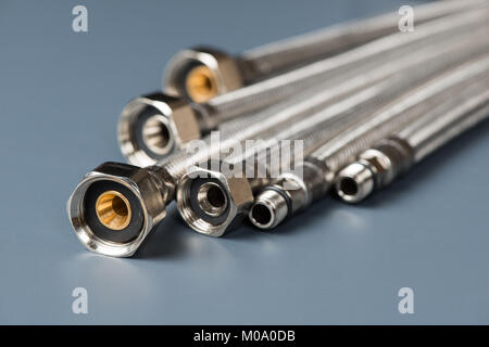 Flexible geflochtenem Edelstahl Wasserschläuche auf grauem Hintergrund Stockfoto