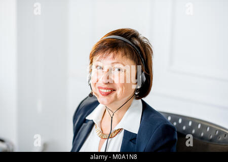Ältere Frau im Gespräch mit Headset im Büro Stockfoto