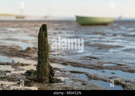 Eine hölzerne Stange im Oare Sümpfe bei Ebbe in der Nähe von Faversham, Kent, England, UK-mit einige Boote und der Insel Sheppey im Hintergrund Stockfoto