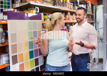 Junge fröhliche Ehepaar miteinander reden und wählen eine Farbe im Haushalt zu speichern. Fokus auf Frauen Stockfoto