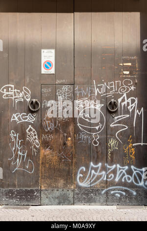 Graffiti gesprüht in weißer Farbe auf eine alte hölzerne Tür in Bologna, Italien Stockfoto