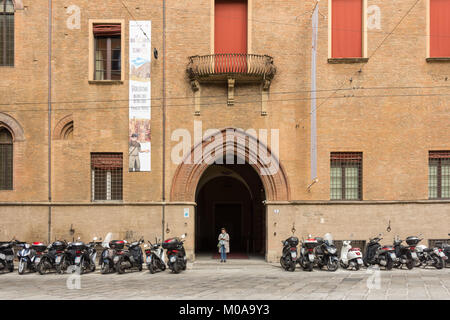 Der Eingang zum Museum Palazzo Pepoli in Bologna Italien mit einer Frau, die in den Eingang und die vielen Roller und Motorräder in einer Reihe geparkt Stockfoto