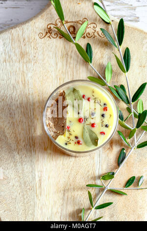 Huhn Leber pate Jar mit zerlassener Butter bedeckt und mit Lorbeerblättern und schwarze und rote Paprika eingerichtet. Ansicht von oben, flach. Kopieren Sie Platz. Stockfoto