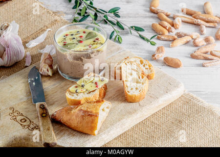 Huhn Leber pate Jar mit zerlassener Butter bedeckt und mit Lorbeerblättern und schwarze und rote Paprika eingerichtet. Stockfoto