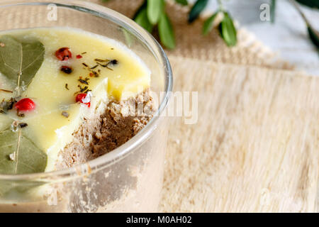 Clos von Huhn Leber pate Jar mit zerlassener Butter bedeckt und mit Lorbeerblättern und schwarze und rote Paprika eingerichtet. Stockfoto