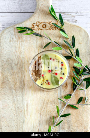 Huhn Leber pate Jar mit zerlassener Butter bedeckt und mit Lorbeerblättern und schwarze und rote Paprika eingerichtet. Ansicht von oben, flach. Kopieren Sie Platz. Stockfoto